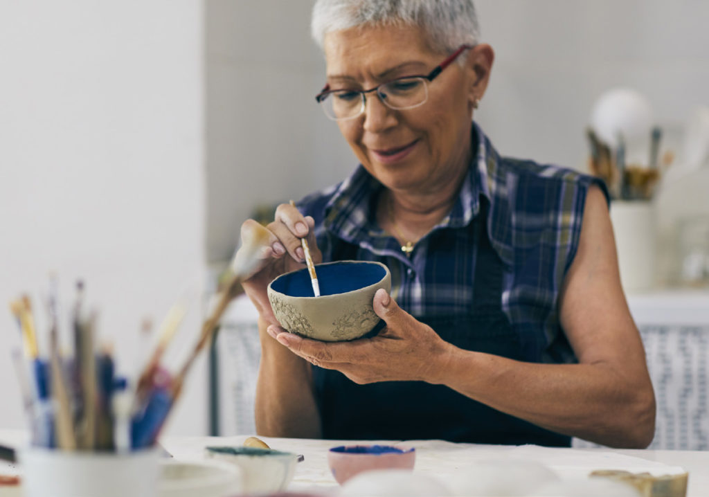 senior woman painting a ceramic bowl