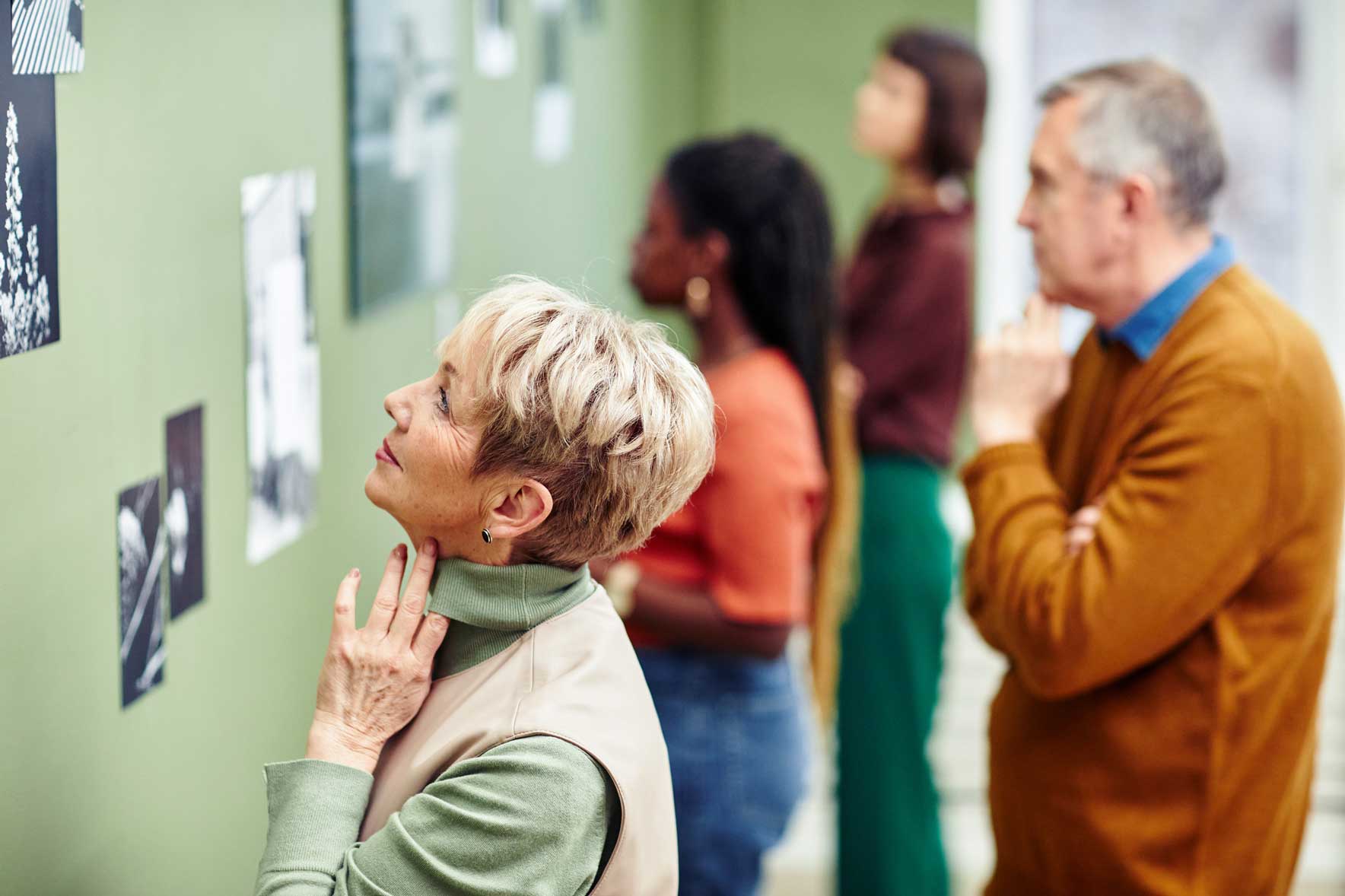 a senior woman observing art on a wall