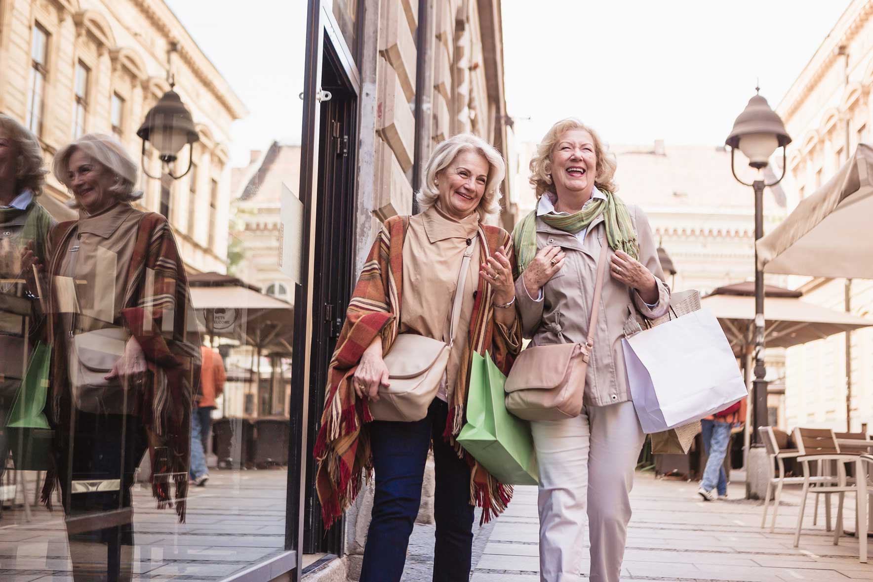 senior women walking down the street smiling and carrying shopping bags